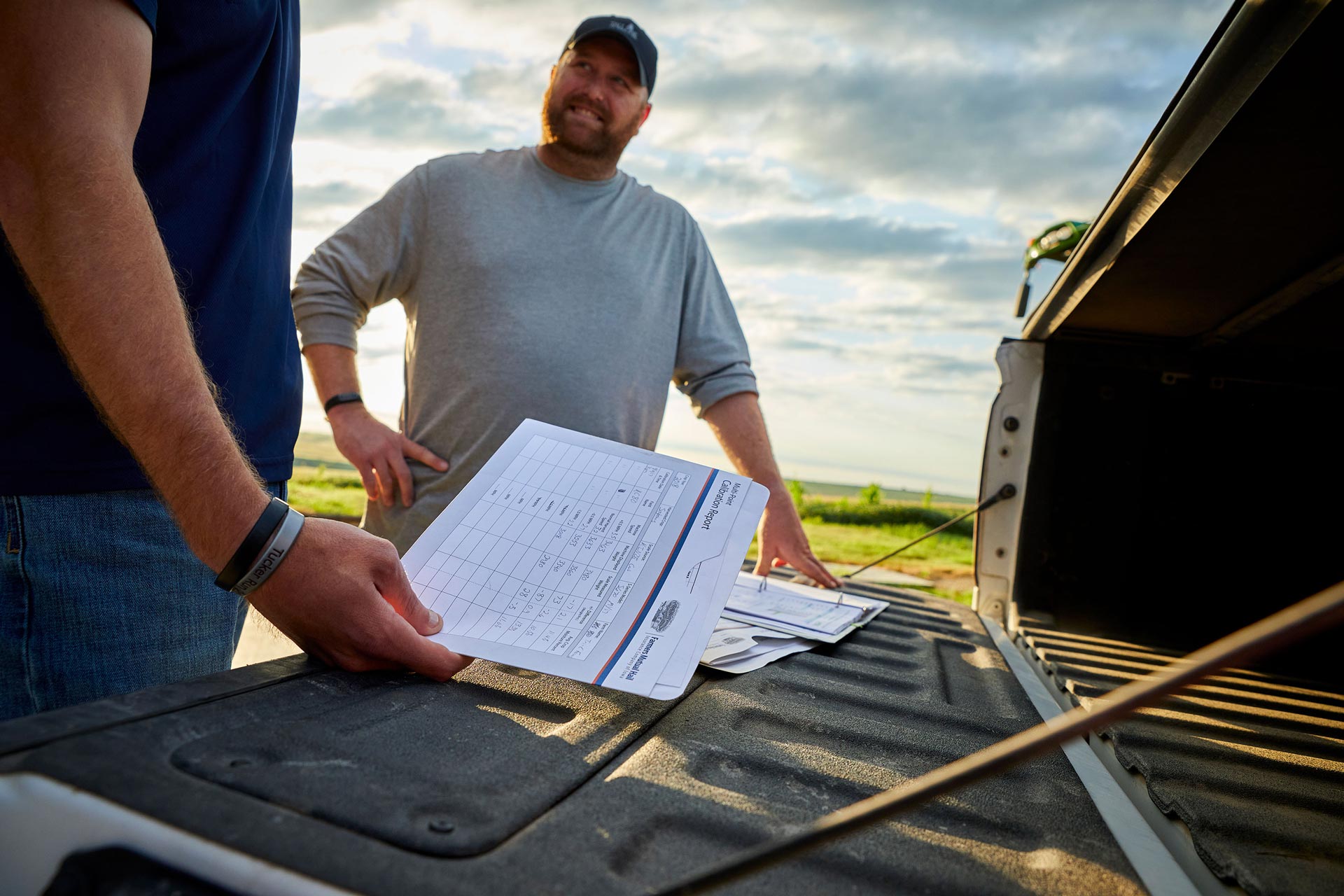 Weller Insurance | FMH | two men looking at calibration paperwork on back of pickup truck